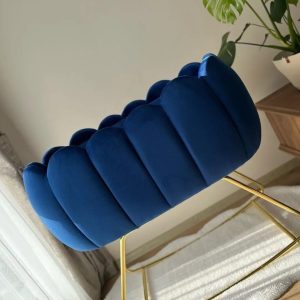 Royal blue velvet Luxury Baby Crib with scalloped panels and gold rocking legs beside a monstera plant